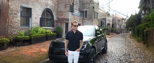 man on a cobblestone street standing in front of a luxury SUV
