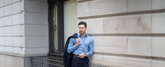 man in crisp dress shirt leaning against a wall