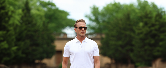 man wearing a white knit polo wearing sunglasses