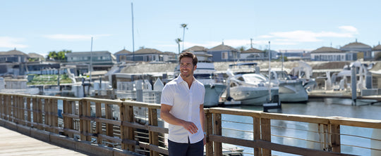 man smiling walking on a dock at a marina in front of boats