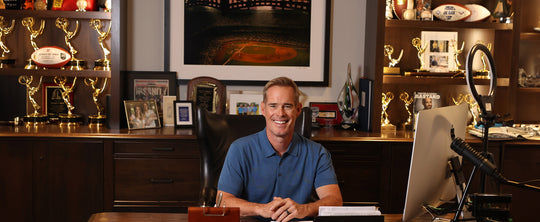 Joe Buck sitting at his desk surrounded by his awards