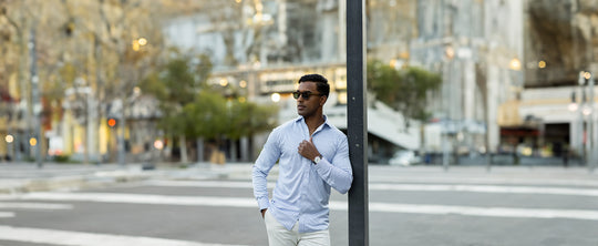 well-dressed man leaning against a pole with a nice watch